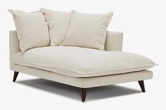 a white couch with two pillows on it's back and one pillow sitting on top of it