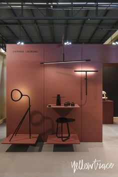 an exhibit with pink walls and black furniture