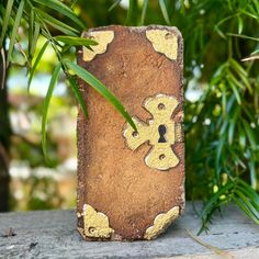 an old piece of wood with yellow paint on it sitting in front of some plants