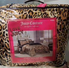 a leopard print suitcase with a pink tag on it's front and the words juicy couture printed in red