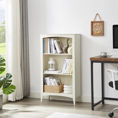 a desk with a computer on top of it next to a book shelf filled with books