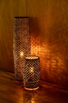 two lamps sitting next to each other on top of a wooden floor in front of a wall