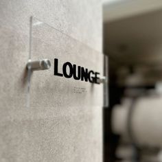 the lounge sign is on the wall next to the toilet paper dispenser