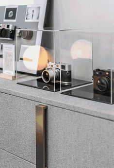 some cameras are sitting on top of a counter in front of a wall with pictures