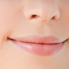 a woman's nose with a gold nose ring on top of her nose and bottom lip