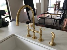 a kitchen sink with two faucets on it and a woman standing in the background