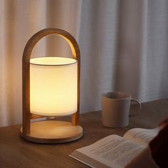 a light that is on top of a table next to a book and coffee cup