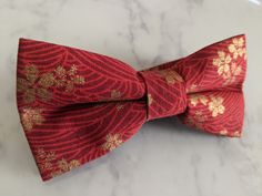 Upgrade your wardrobe in style with this stunning red and gold floral pattern bow tie. Perfect gift for him, this unique adjustable bow tie will elevate any occasion including weddings, birthdays and anniversaries. Comes pre-tied. Red Bow Tie As Gift, Elegant Red Bow With Butterfly Knot, Red Standard Tie Bow As Gift, Elegant Red Bow Tie As Gift, Elegant Red Bow For Gift, Elegant Red Adjustable Bow, Red Bow Tie With Butterfly Knot For Gift, Red Bow Tie Back Bow As Gift, Red Bow With Tie Back As Gift