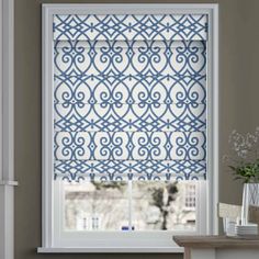 a blue and white roman blind in front of a window with an ornate pattern on it