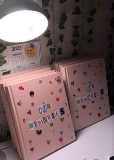 two pink notebooks with magnets on them sitting next to a lamp and wallpaper