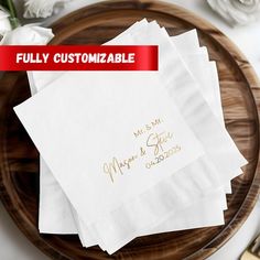 four personalized napkins on top of a wooden platter with flowers and forks