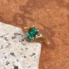 Estate/ vintage polished 10KT yellow gold ring with center, lab-created emerald + surrounding white diamonds. Timeless gold ring with a beautiful, vibrant green emerald! Size 7.25 Can be resized for an additional fee Weight: 1.8g (2) 1 pt genuine, white diamonds; SI clarity; H color Approx. 6mm x 4mm lab-created, green, rectangle center emerald Excellent estate condition Green Emerald Ring With Diamond Accents For Promise, Green Emerald Promise Ring With Diamond Accents, Emerald Rings With Diamond Accents For May Birthstone, Green Emerald Ring With Diamond Accents As Gift, 14k Gold Emerald Cut Emerald Ring For May Birthstone, Classic Rectangular Emerald Gemstone Ring, Gold Emerald Ring With Diamond Accents, Classic Diamond Ring With Accent Stones For May Birthstone, Green Emerald-cut Jewelry With Diamond Accents