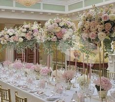 a long table is set with pink and white flowers in tall vases on the tables