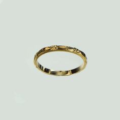 a gold wedding ring with an intricate design on the inside and outside, set against a plain white background