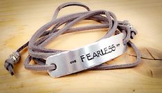 This Bracelet is sure to be the most versatile and unique of your accessory collection!   This particular Bracelet Wrap is hand stamped with the phrase "Fearless". Each piece has an engraved rectangle aluminum plate with curved and distressed edges.  40 inches of suede cord (your choice in color) is strung through each end of the plate and is finished with silver beads. Just wrap this unique bracelet around your wrist as many times as you wish and tie the ends together.  You can tuck the ends to allow the beads to give more character to the wrap or let the ends dangle.  This wrap can be worn in the shower or while washing your hands, and is easily untied for removal.   You can show your personality by having this unique bracelet stamped with words, quotes, names, monograms, or song lyrics Handmade Adjustable Meaningful Bracelets, Silver Leather Bracelet With Hand Stamped Details For Everyday, Adjustable Silver Leather Bracelet With Hand Stamped Details, Adjustable Silver Leather Bracelet Hand Stamped, Bohemian Hand Stamped Bracelets For Gift, Bohemian Hand Stamped Bracelets For Gifts, Bohemian Hand Stamped Bracelets As Gift, Bohemian Hand-stamped Bracelets For Gifts, Inspirational Adjustable Stamped Bracelets