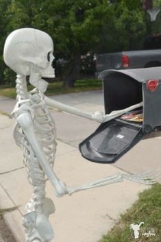 a skeleton holding a mailbox on the sidewalk