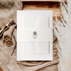 a white envelope with a monogrammed palm tree on it and a pair of scissors