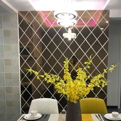 a vase with yellow flowers on a dining table in front of a wall mounted mirror