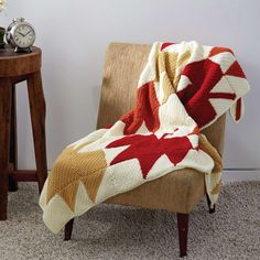 a chair with a blanket on top of it next to a table and an alarm clock