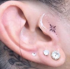 a man with three piercings on his ear and behind the ear is a flower