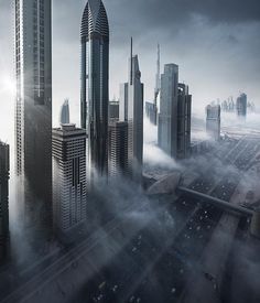 an aerial view of a city with skyscrapers in the fog and sun shining through clouds