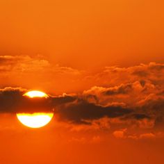 the sun is setting behind some clouds in the sky