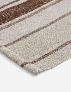 an area rug with brown and white stripes on the bottom, in front of a white background