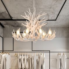 a white chandelier hanging from the ceiling in a room with clothes on hangers