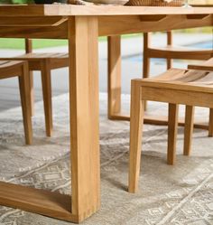 a wooden table with two chairs next to it on a rug in front of a pool