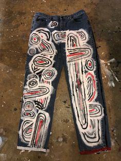 a pair of jeans that have been painted with different colors and designs on them, sitting on the ground