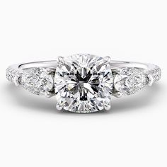 a diamond engagement ring with three stones on the band and an oval shaped center stone