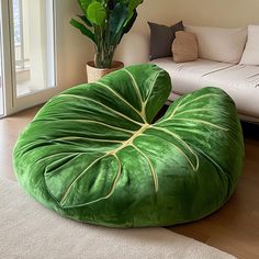 a green bean bag chair sitting on top of a wooden floor next to a white couch