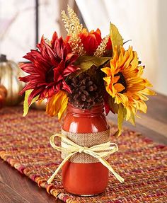 a vase filled with flowers sitting on top of a wooden table next to a pumpkin