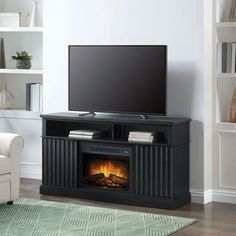 a flat screen tv sitting on top of a black entertainment center next to a fire place