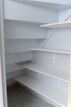 an empty white shelf in the corner of a room