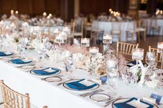 a long table is set with blue and white place settings, silverware, and candles