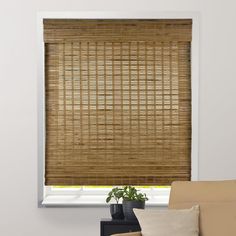 a living room with a couch and window covered in bamboo blinds