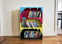 a book shelf with books on it in the middle of a wooden floored room