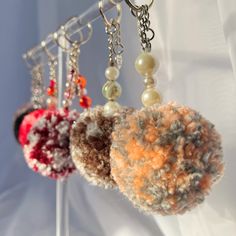 three key chains hanging from hooks with beads on them and two balls of yarn attached to them