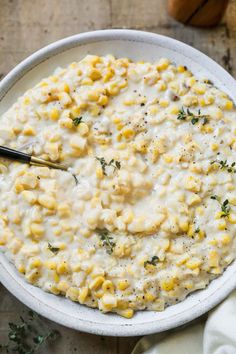 a white bowl filled with macaroni and cheese on top of a wooden table