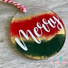 a glass ornament with the word merry written on it and a candy cane