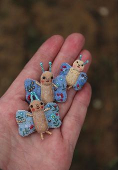 hand holding three small stuffed animals in it's palm, one is blue and the other is brown