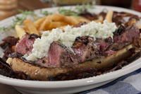 a close up of a plate of food with meat and french fries on the side