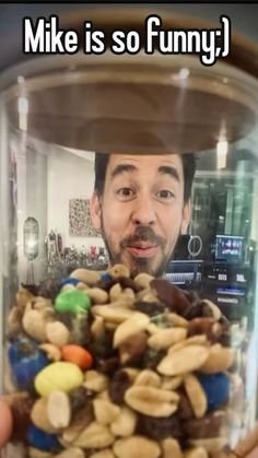 a man is holding up a jar full of nuts and chocolates with the caption mike is so funny