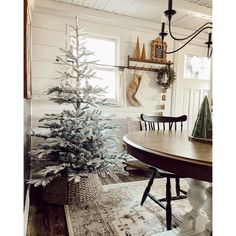 a white christmas tree sitting in the middle of a room next to a table and chair