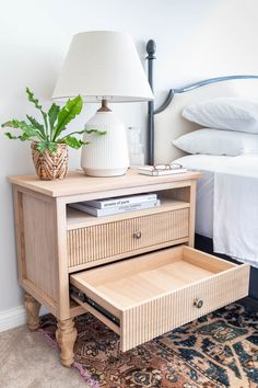 a bedroom with a bed, nightstand and lamp on the side table in front of it