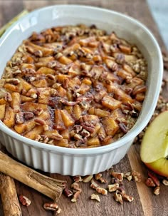 an apple and cinnamon baked oatmeal in a white dish on a wooden cutting board