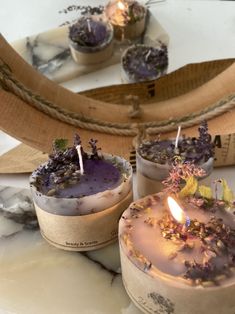 three candles are sitting on a table next to a basket with lavenders in it