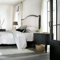 a bedroom with white bedding and black furniture