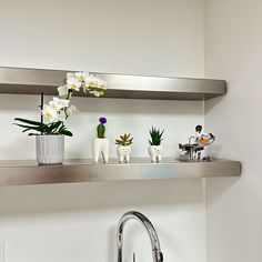 a kitchen sink sitting under a metal shelf above a faucet with flowers on it